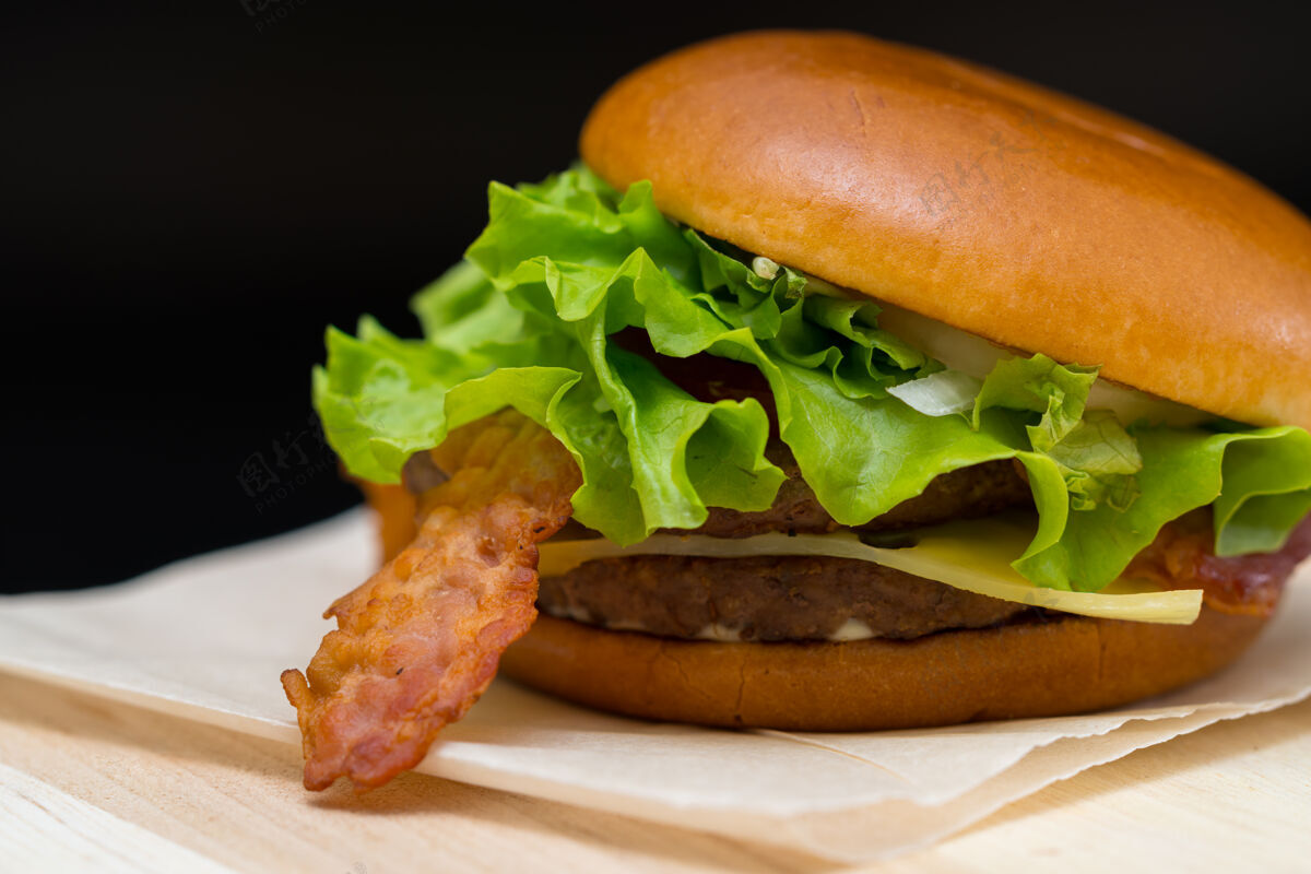 餐厅美味的培根和芝士汉堡 用生菜装饰在一张纸上 在自助餐厅作为外卖或快餐新鲜面包汉堡