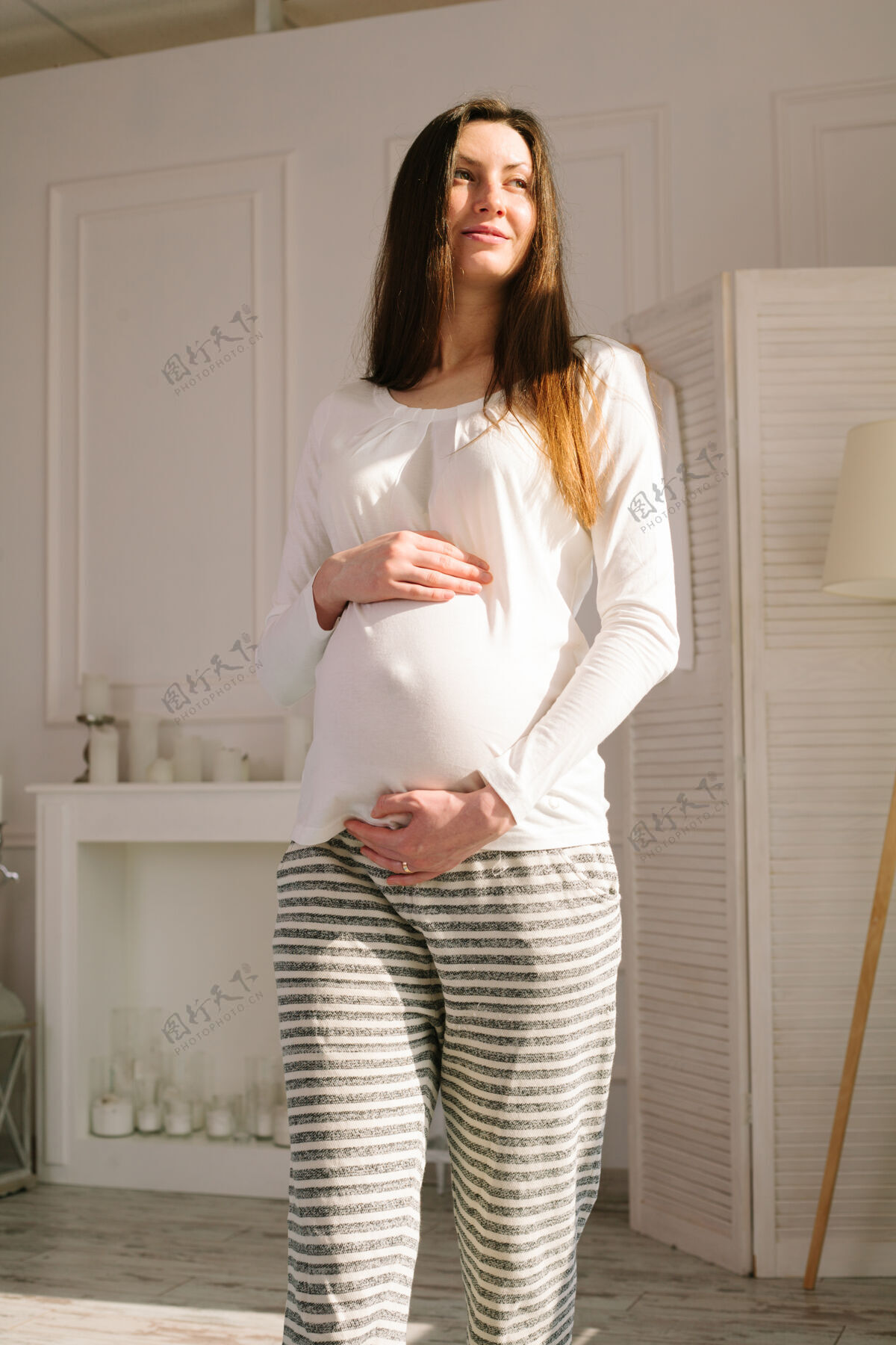 年轻孕妇在家走路抱着肚子母亲父母大