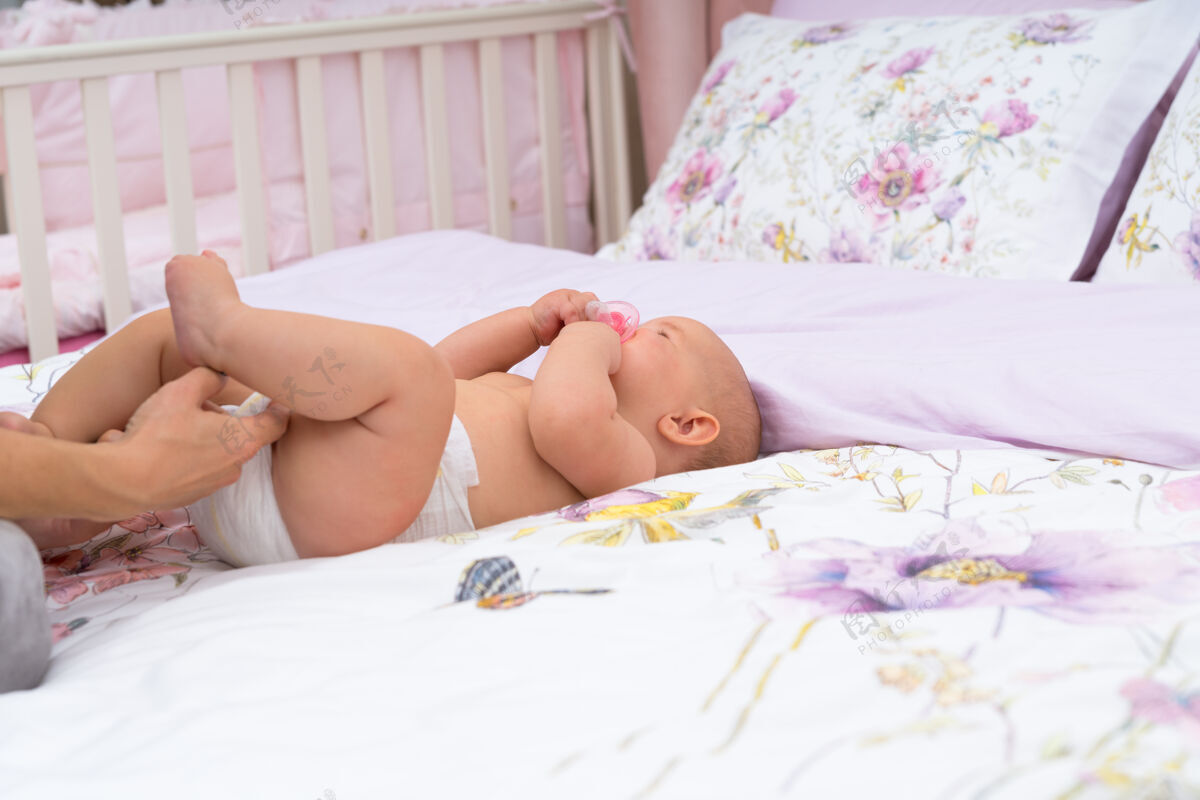 女孩妈妈们用手检查她的婴儿尿布 而她躺在床上的亚麻布上 用复印空间近距离观察新生儿天真母性