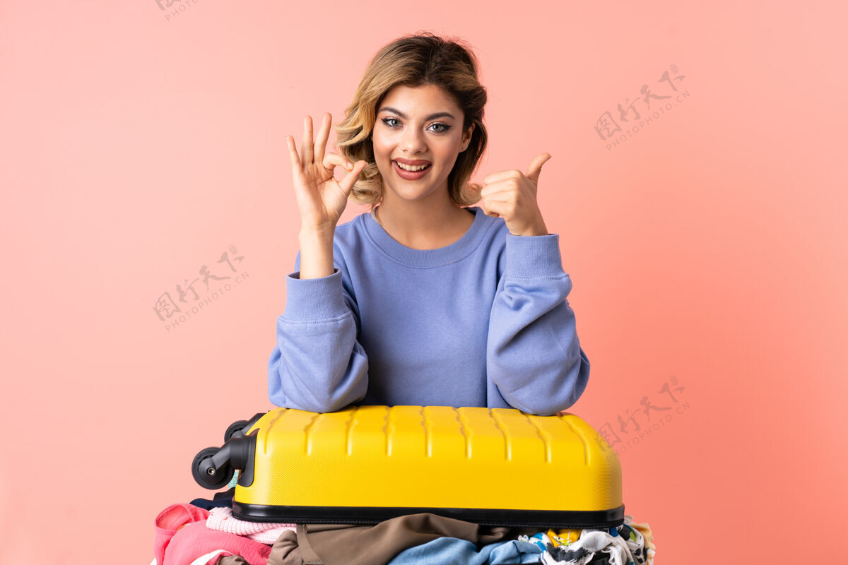 表情一个十几岁的女人 拿着色拉在蓝色的桌子上 摆着ok的手势和竖起大拇指的姿势Ok青少年朋友