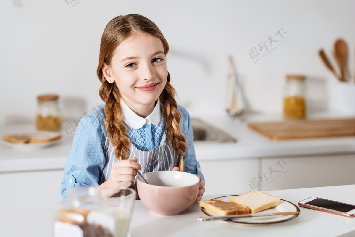 花生酱热情的开始乐观可爱可爱的孩子坐在厨房的桌子旁 享受着由麦片 三明治和牛奶组成的早餐餐碗吃