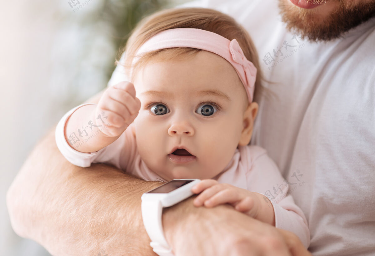 童年不堪重负情感甜蜜可爱的小女婴躺在爸爸的手里 一边看着别处 一边表达着兴趣和喜悦放松可爱可爱