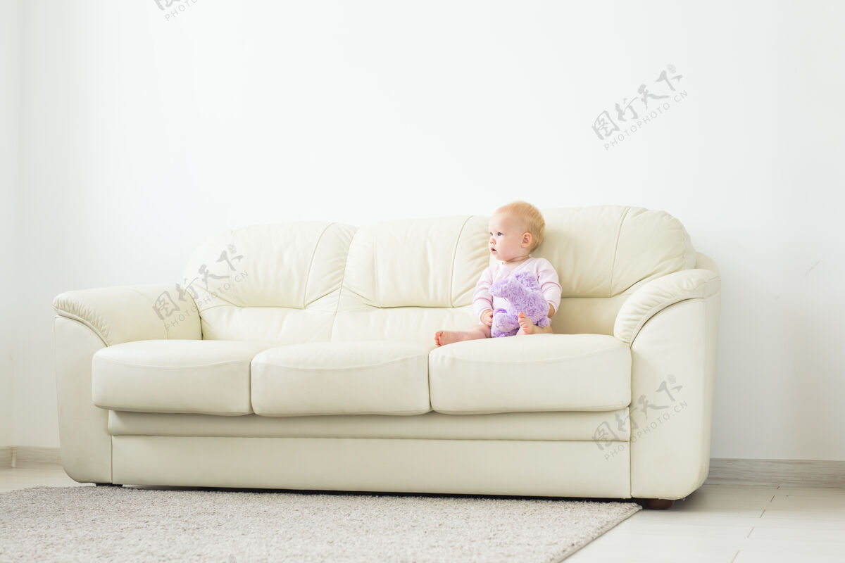 男孩童年 婴儿期和人的概念-快乐的小女婴坐在家里的沙发上婴儿婴儿小
