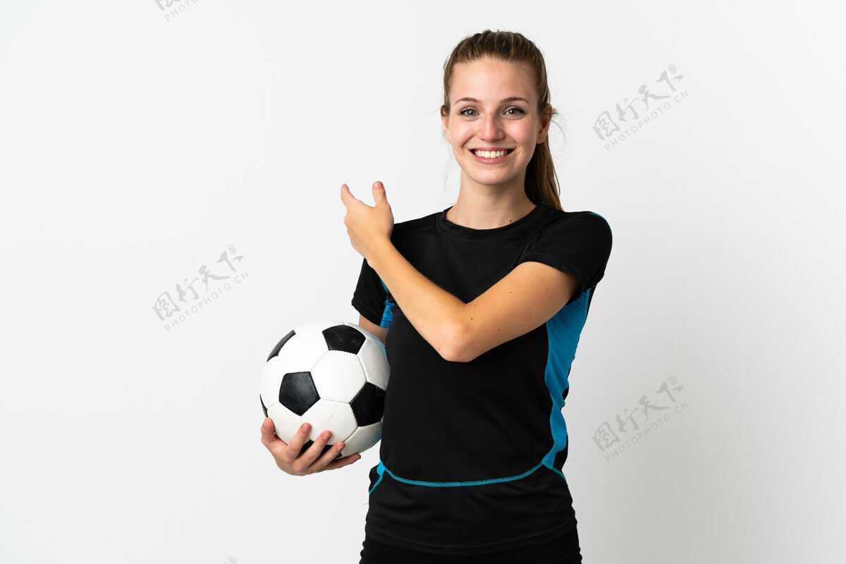 手势年轻的足球运动员女子孤立地站在白色背景上 指着旁边的产品展示足球指点肖像