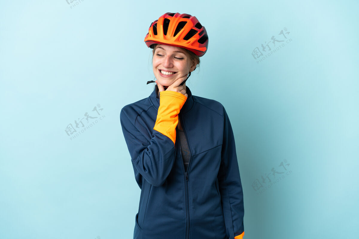 笑一个年轻的骑自行车的女人被隔离在蓝色的背景下 面带微笑地看着旁边快乐女人骑