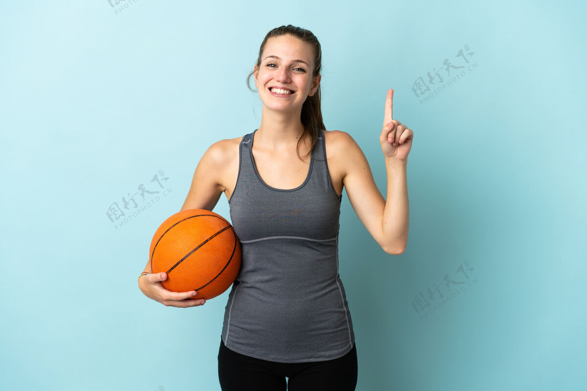 女人在蓝色背景上孤立地打篮球的年轻女子提出了一个好主意表情健身爱好