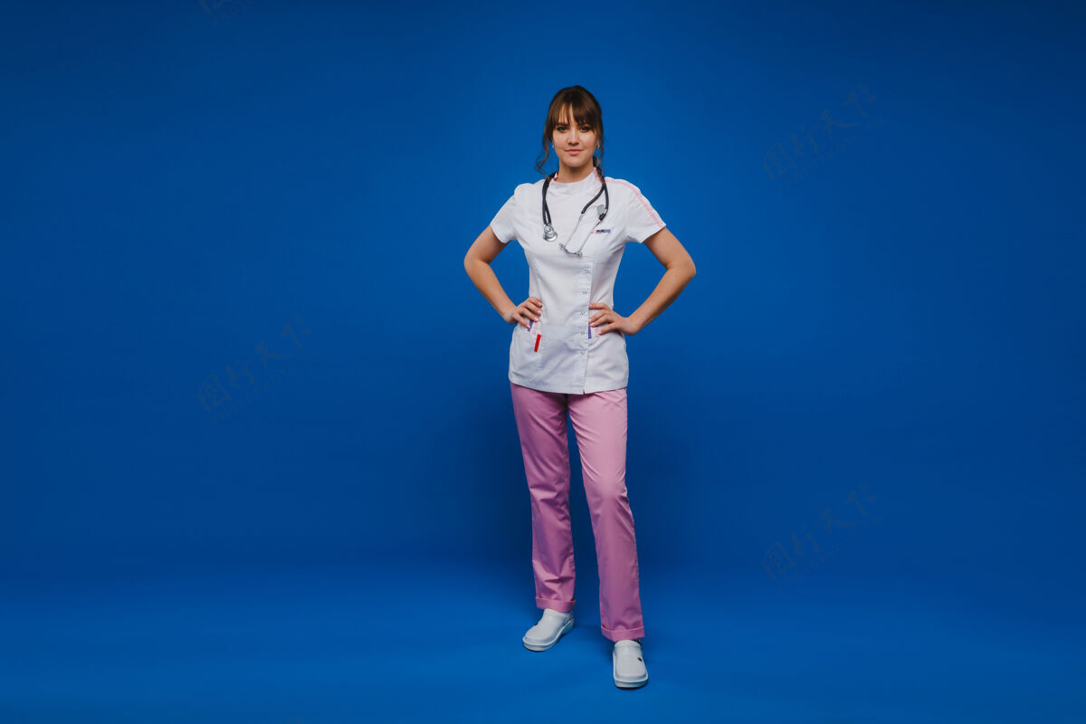 医学年轻的女医生用听诊器隔离在蓝色背景上护理专业外套