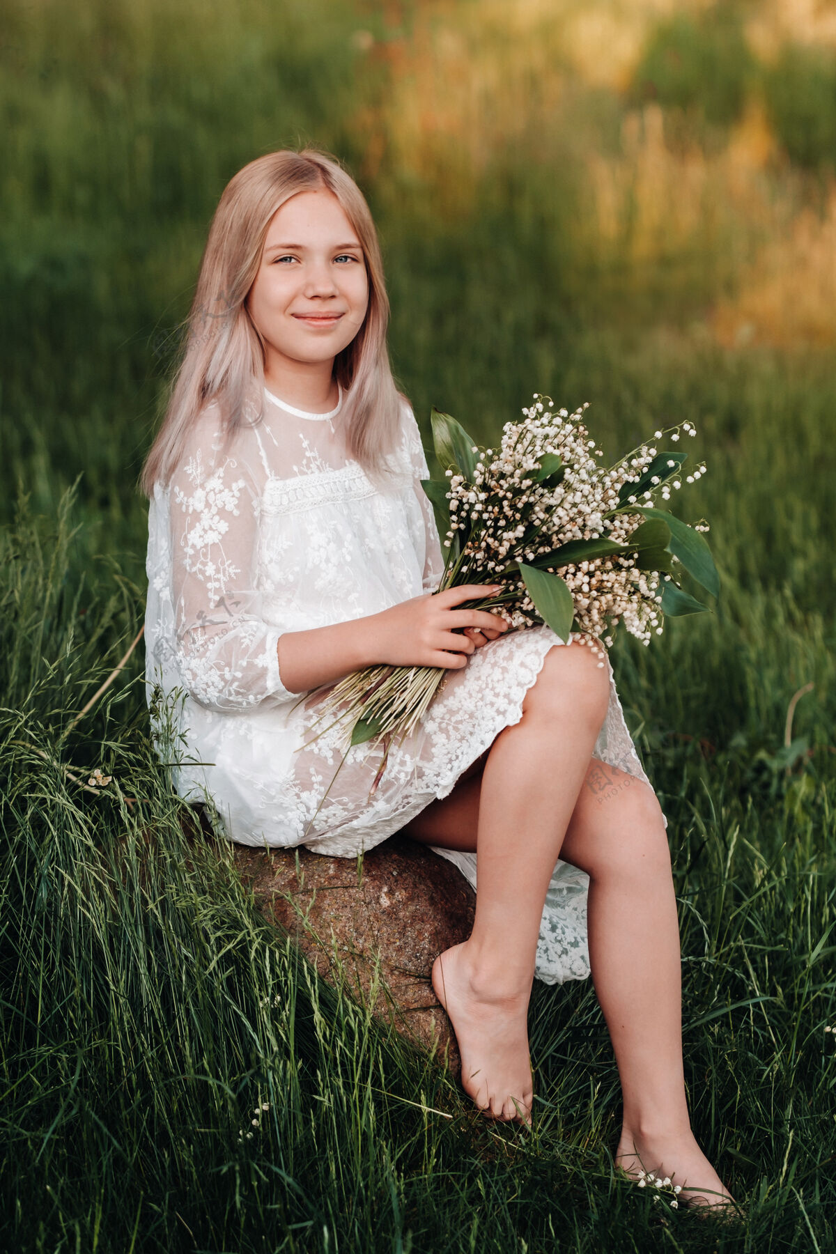 爱一个美丽的九岁金发女孩 留着一头长发 穿着白色长裙 手持一束铃兰花 在大自然中漫步公园夏天日落家庭衣服金发