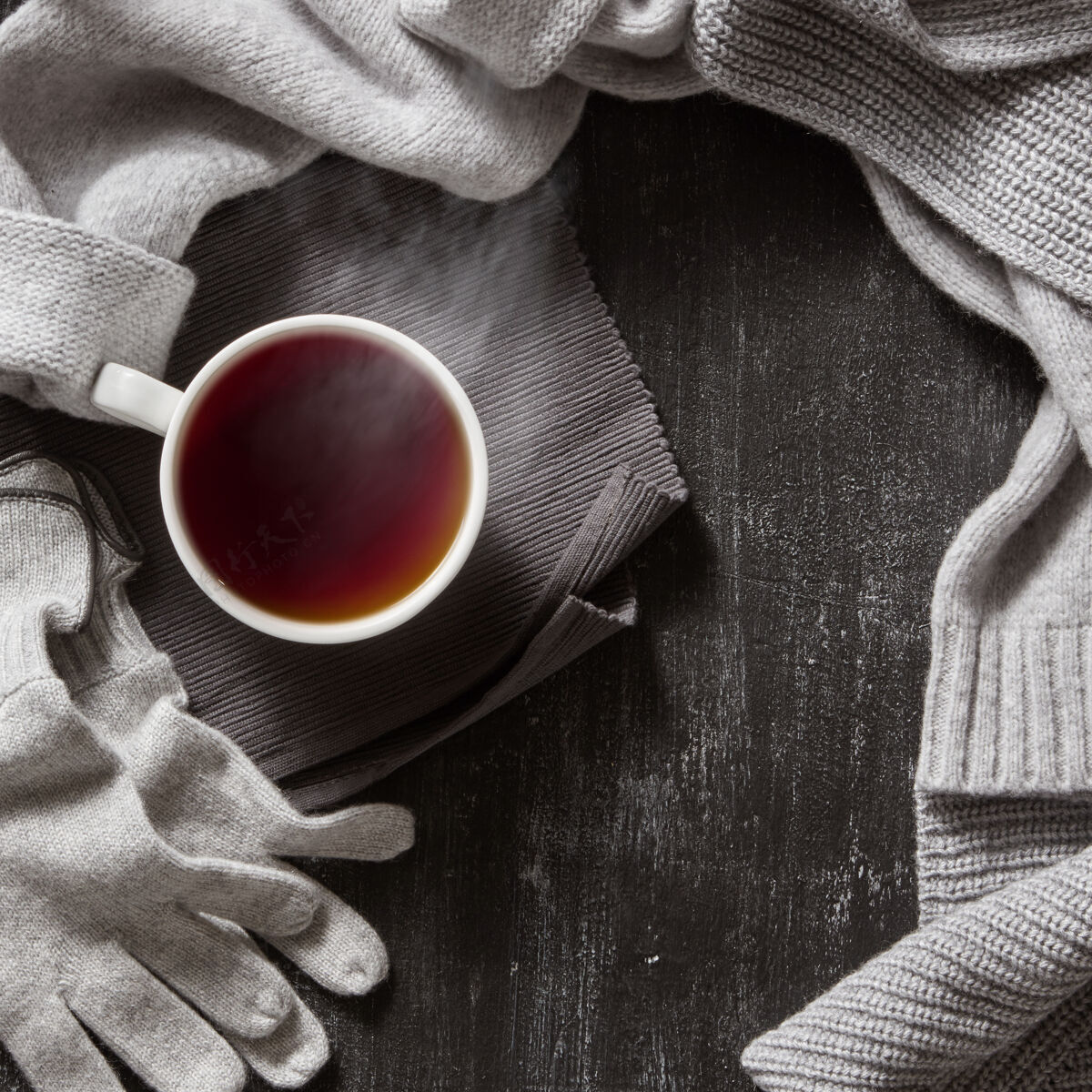 乡村针织手工羊毛服装.秋季或者冬天的衣服和一杯热茶杯放在黑色的表面上针织品架子编织