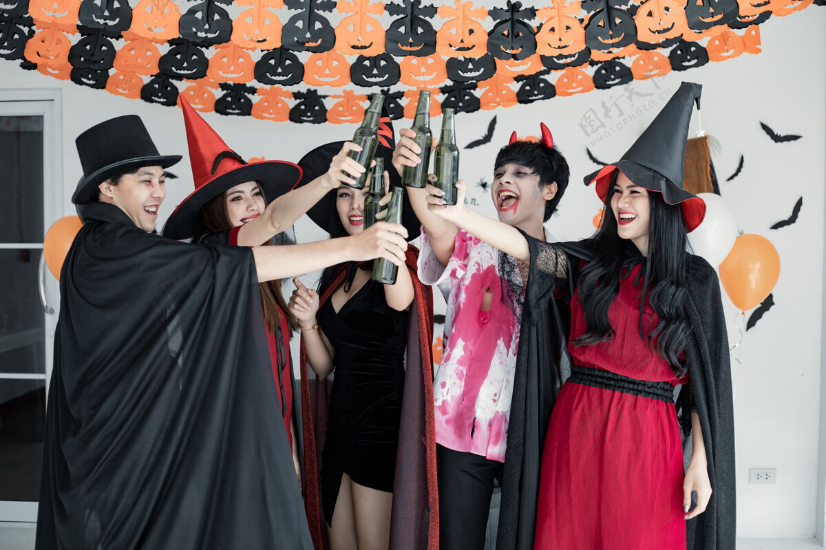 气球一群年轻的亚裔女巫穿着古装 与巫师一起欢庆万圣节派对 一起跳舞喝酒 在酒吧里喝醉房间.组泰语青少年万圣节概念在家里过万圣节节日年轻泰国