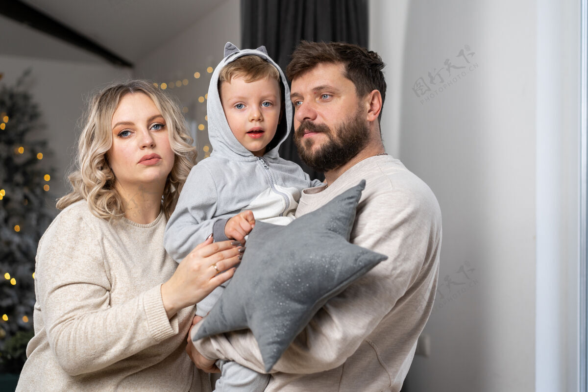 圣诞节幸福的家庭概念丈夫抱着肚子怀孕的妻子站在室内客厅沙发旁高加索男女怀孕新生活概念爱情还有关心护理拥抱两个