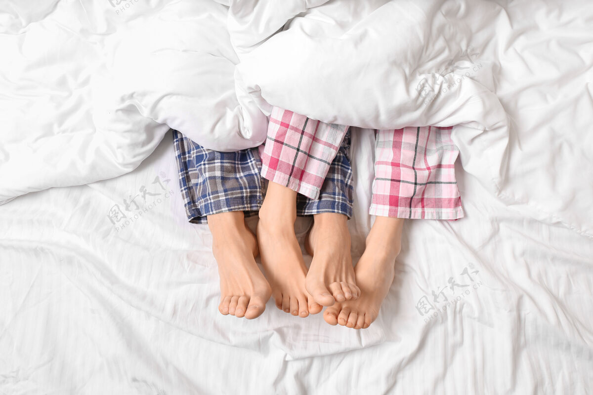 腿躺在床上的年轻夫妇 顶视图男人女人房子