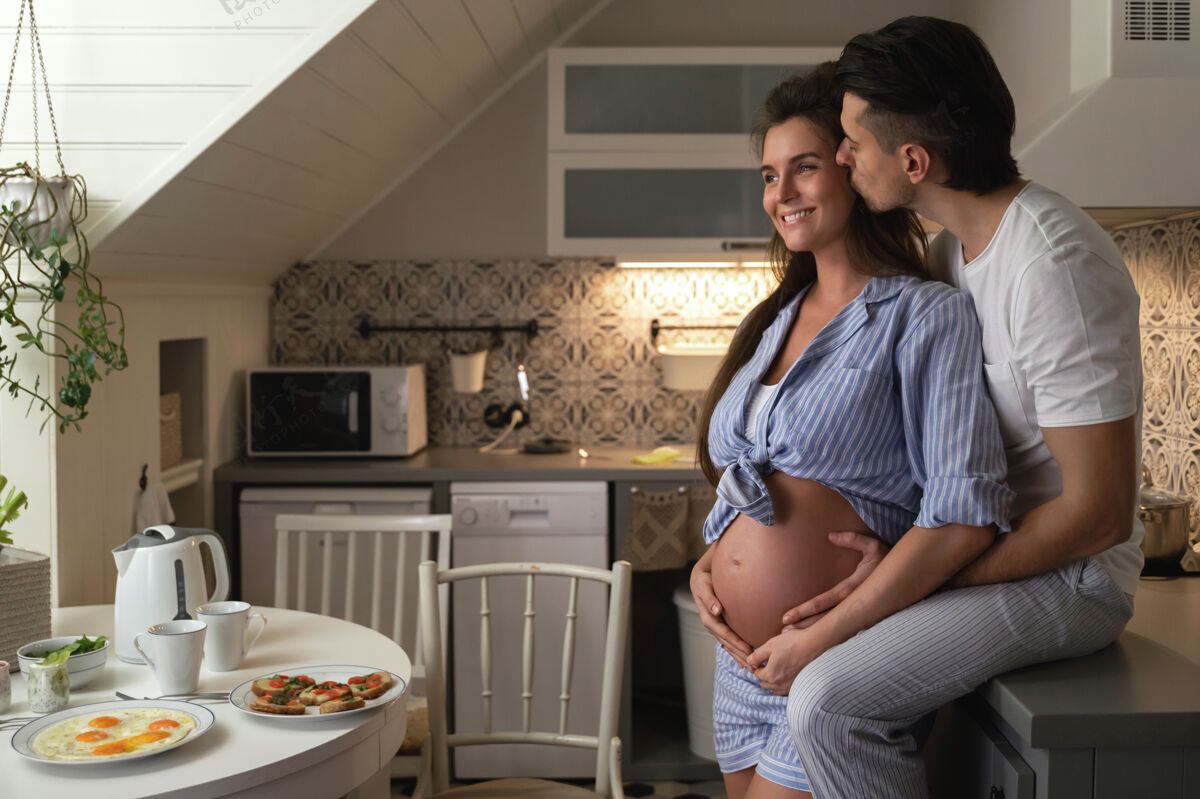 积极一对年轻幸福的夫妇在等待宝贝老公还有他怀孕的妻子在厨房吃早餐夫妇舒适关系