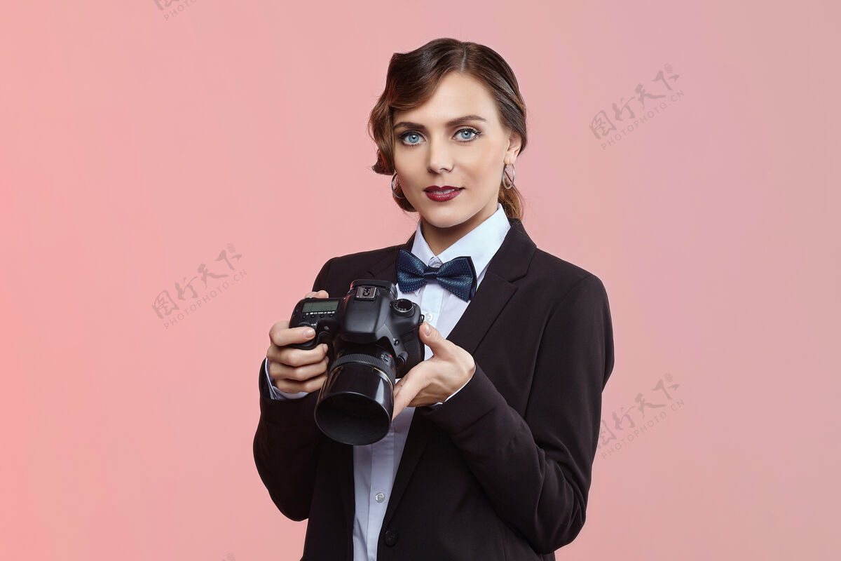 肖像漂亮的女摄影师在一个男人的西装和复古发型的粉红色背景人物表情年轻