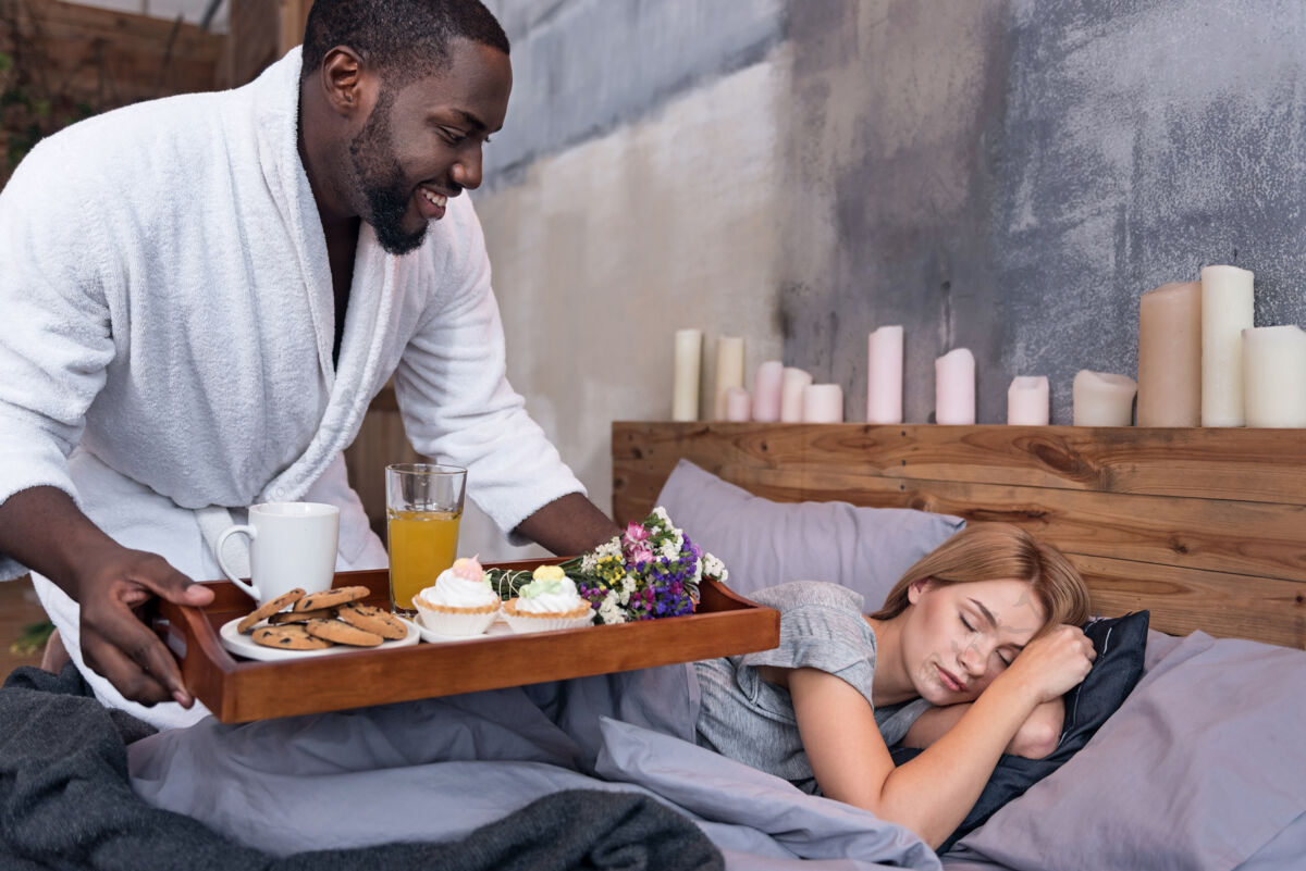 关系显示爱体贴年轻的非洲男人在妻子睡觉的时候给她送早餐 一起享受周末周末休闲赛车