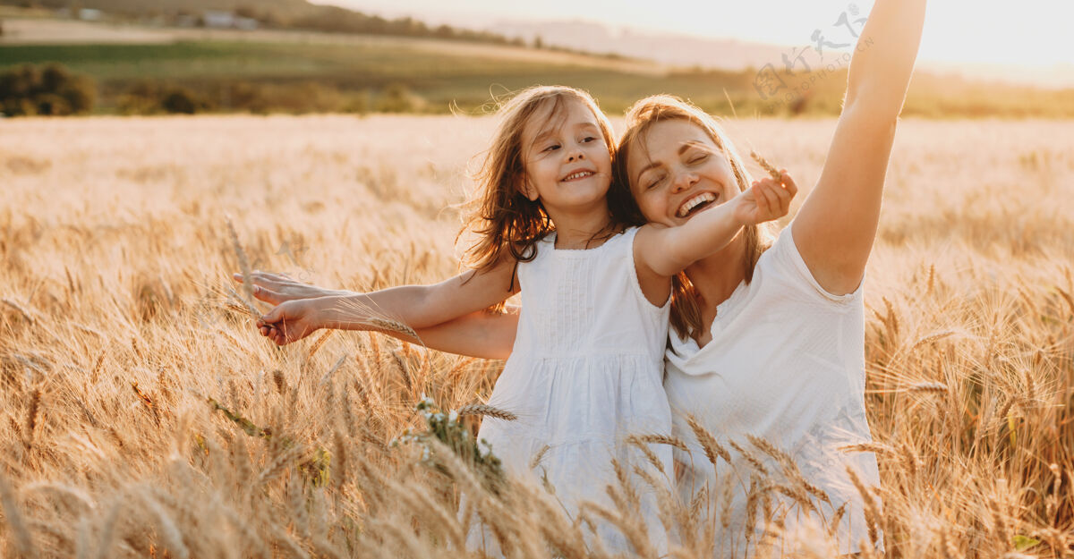 爱一位快乐的年轻母亲和她可爱的女儿在麦田里玩耍和欢笑的肖像自由的概念光笑年轻