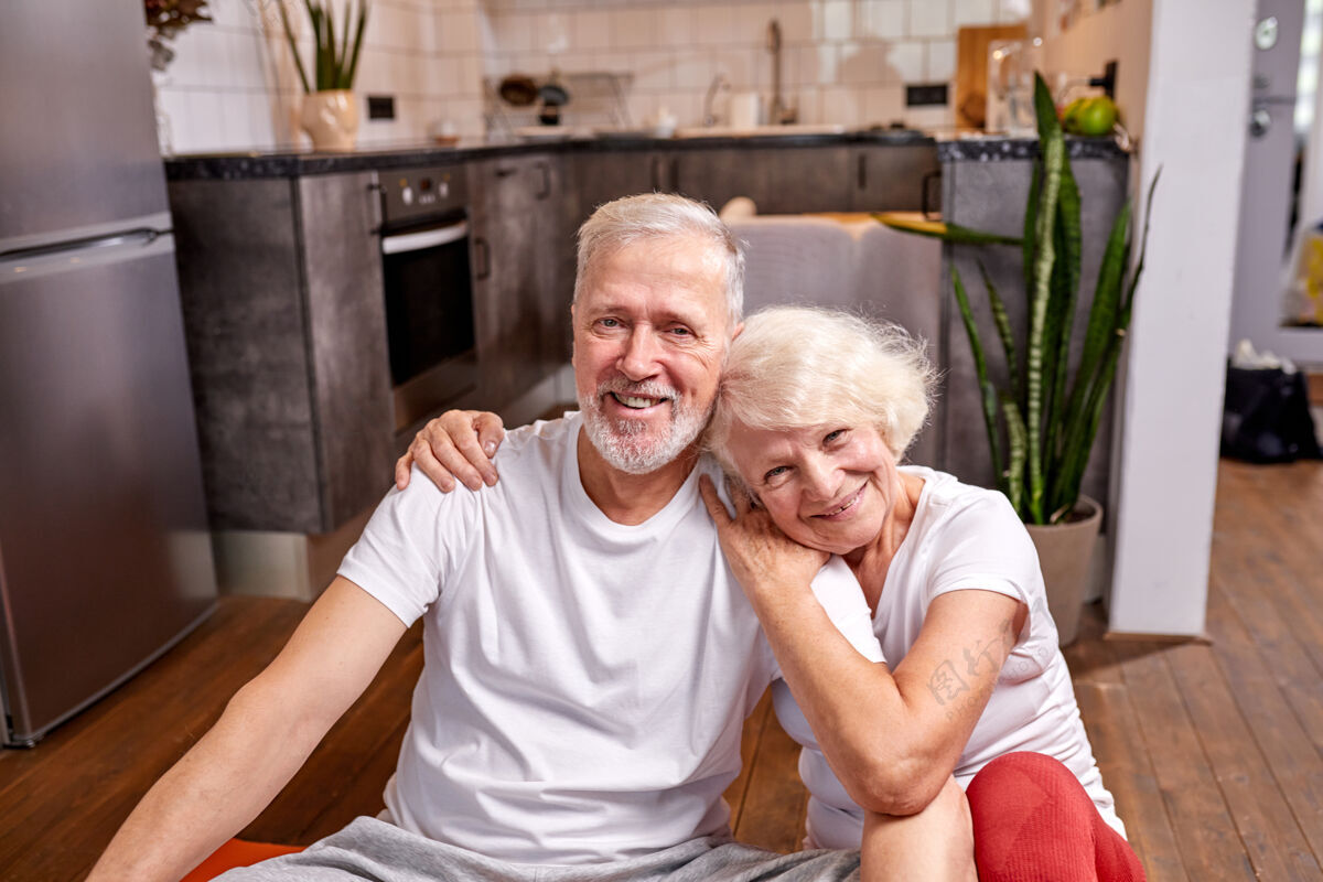 老人运动型男女50-60岁坐在地板上休息锻炼后 运动锻炼 看着相机微笑 快乐在一起男人爱妻子
