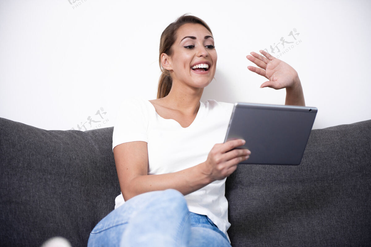 女性美丽的女人在客厅的沙发上用她的平板电脑设备屏幕技术