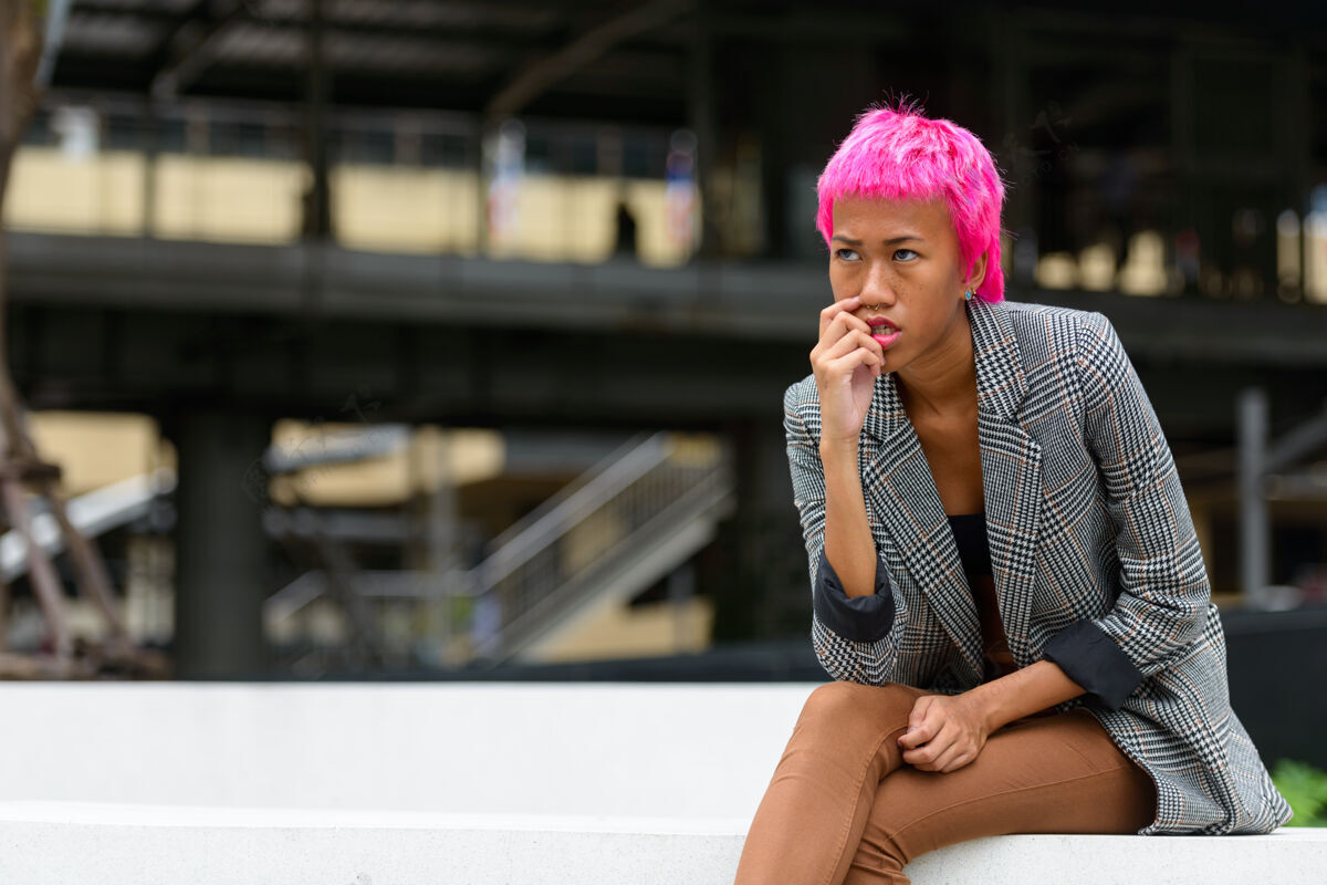 20多岁年轻叛逆的亚洲女商人的画像 粉红色的头发 在城市街道户外思考态度道路