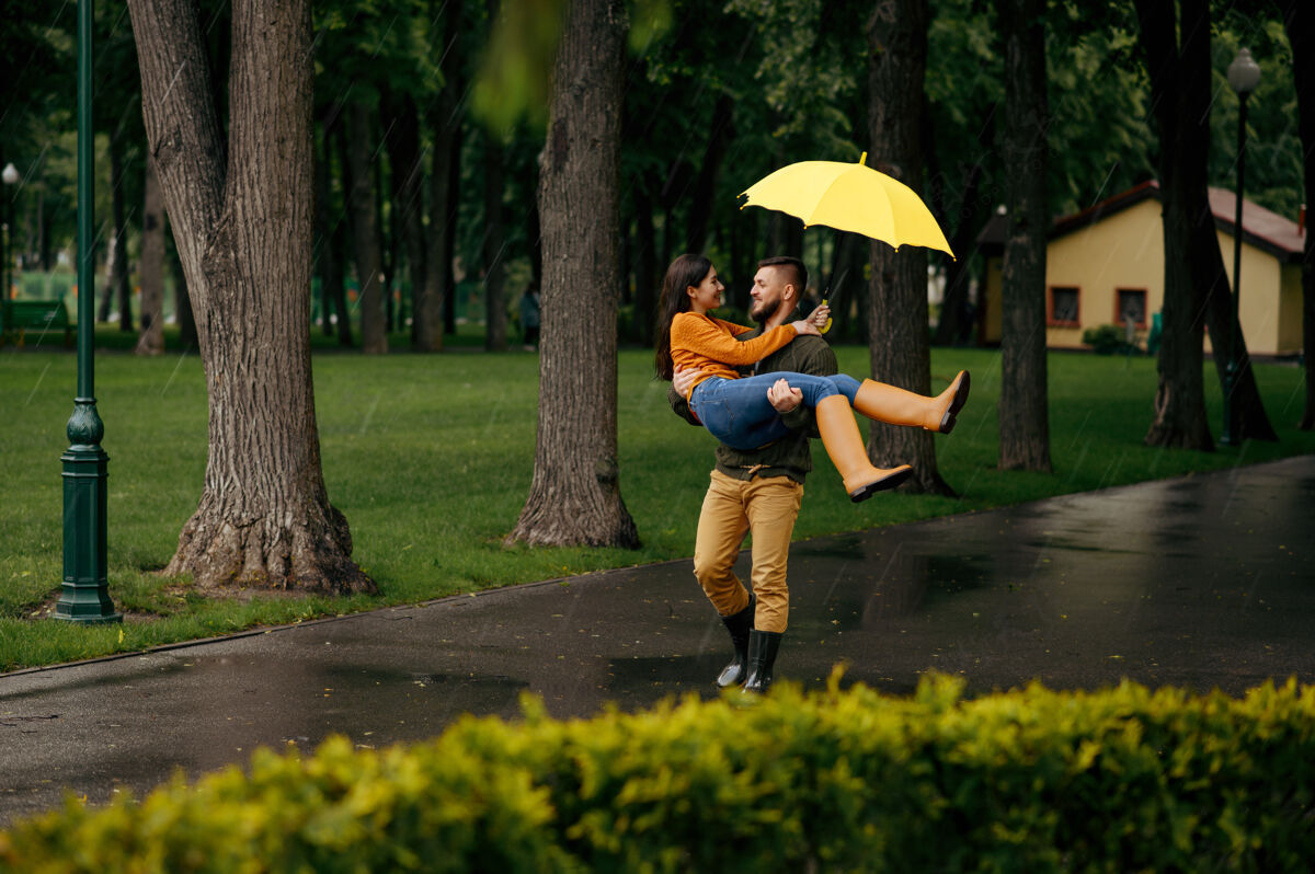 夫妇一对幸福的情侣在夏日的雨中放松戴曼雨中的女人在雨伞下拥抱 散步路上的浪漫约会 巷子里的潮湿天气拥抱家庭女孩