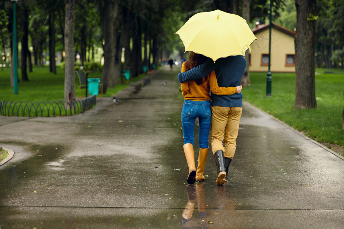 森林在夏季公园 背景 雨天 拥抱着伞的情侣戴曼女人在雨中的小路上悠闲地走着 小巷里的天气潮湿一对拥抱散步