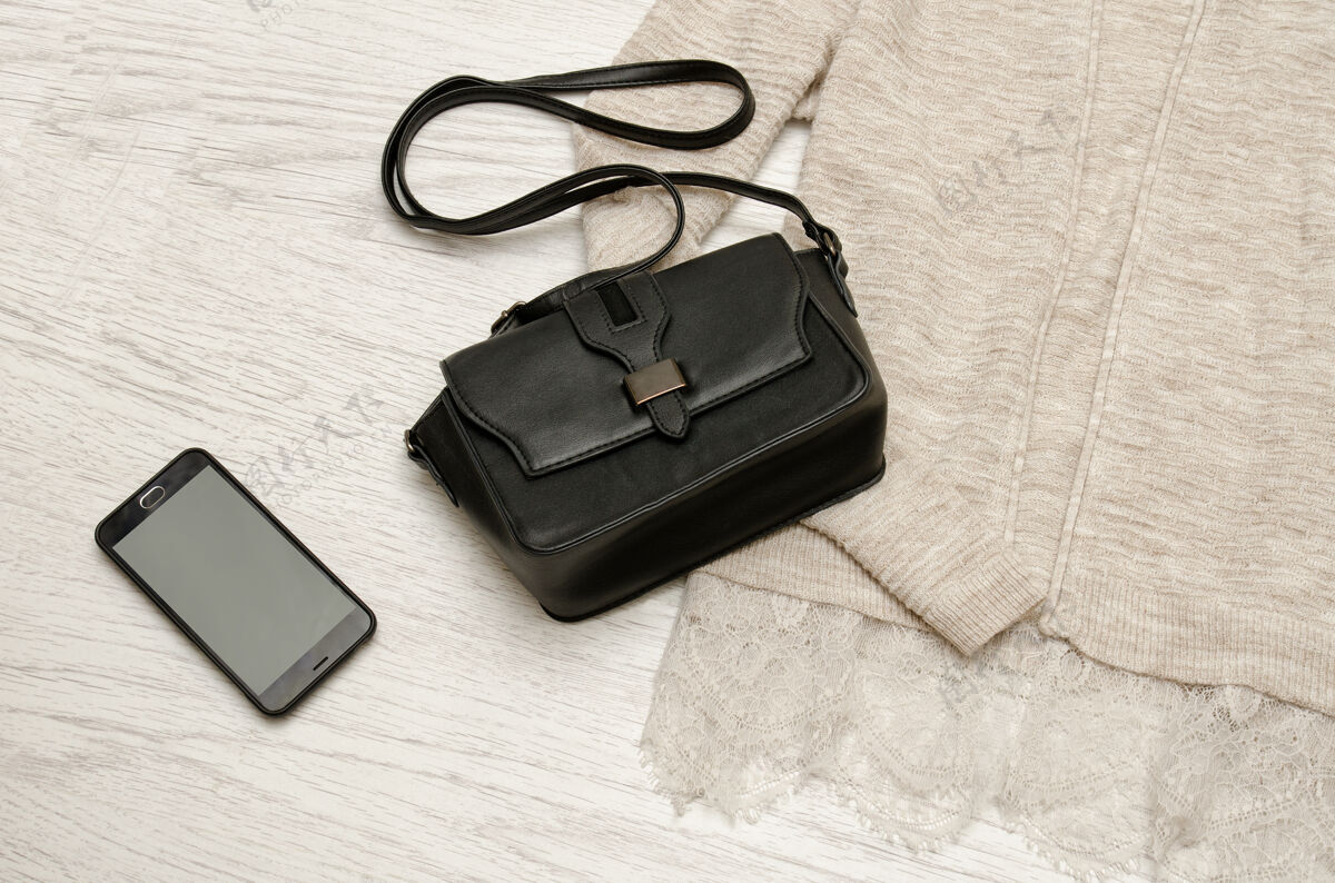 景观米色的黑色手提包和手机开衫.木制背景时尚概念 顶视图时尚空间文本手提包