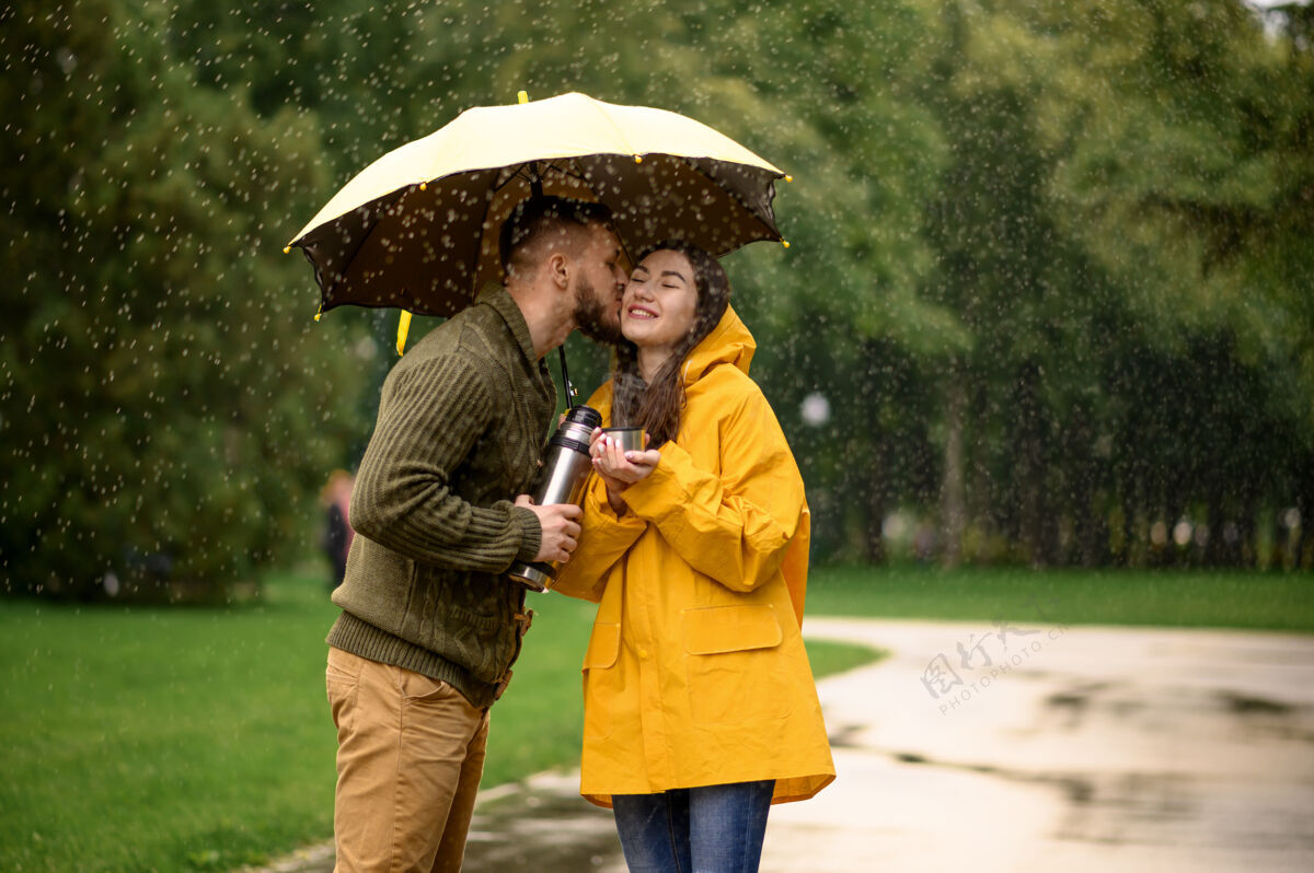夫妇公园热茶情侣 夏日多雨戴曼雨中的女人站在雨伞下 漫步小径上的浪漫约会 小巷里的潮湿天气男性拥抱丈夫