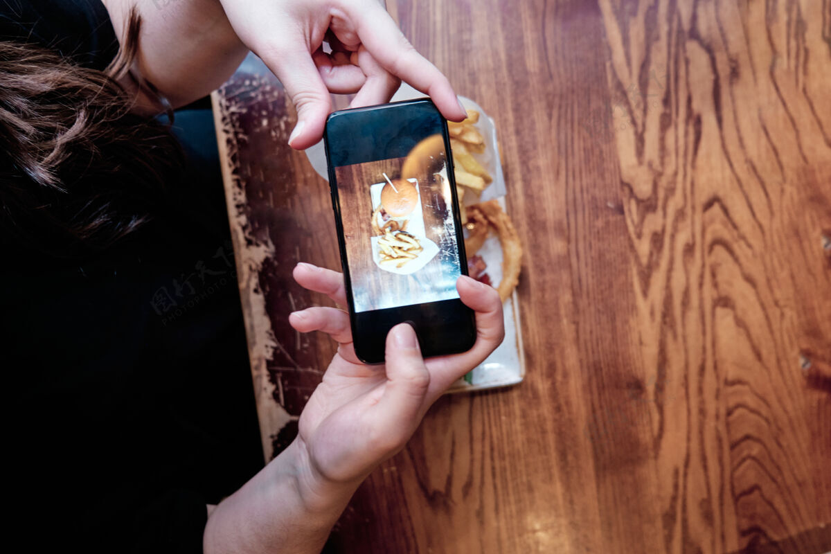 年轻人手拿手机拍午餐照片分享社交媒体午餐薯条科技