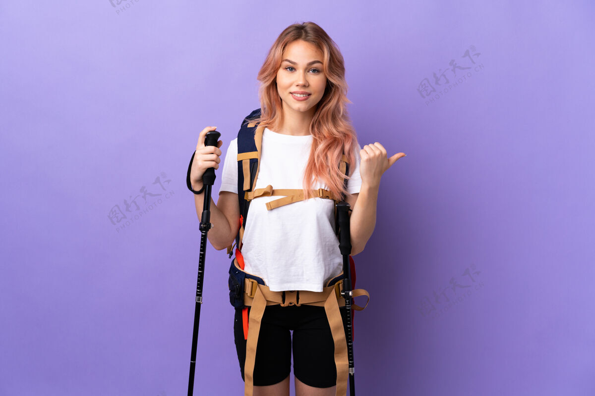 手指女孩背着背包和登山竿就孤立地指着紫色的边上呈现一个产品远足散步显示