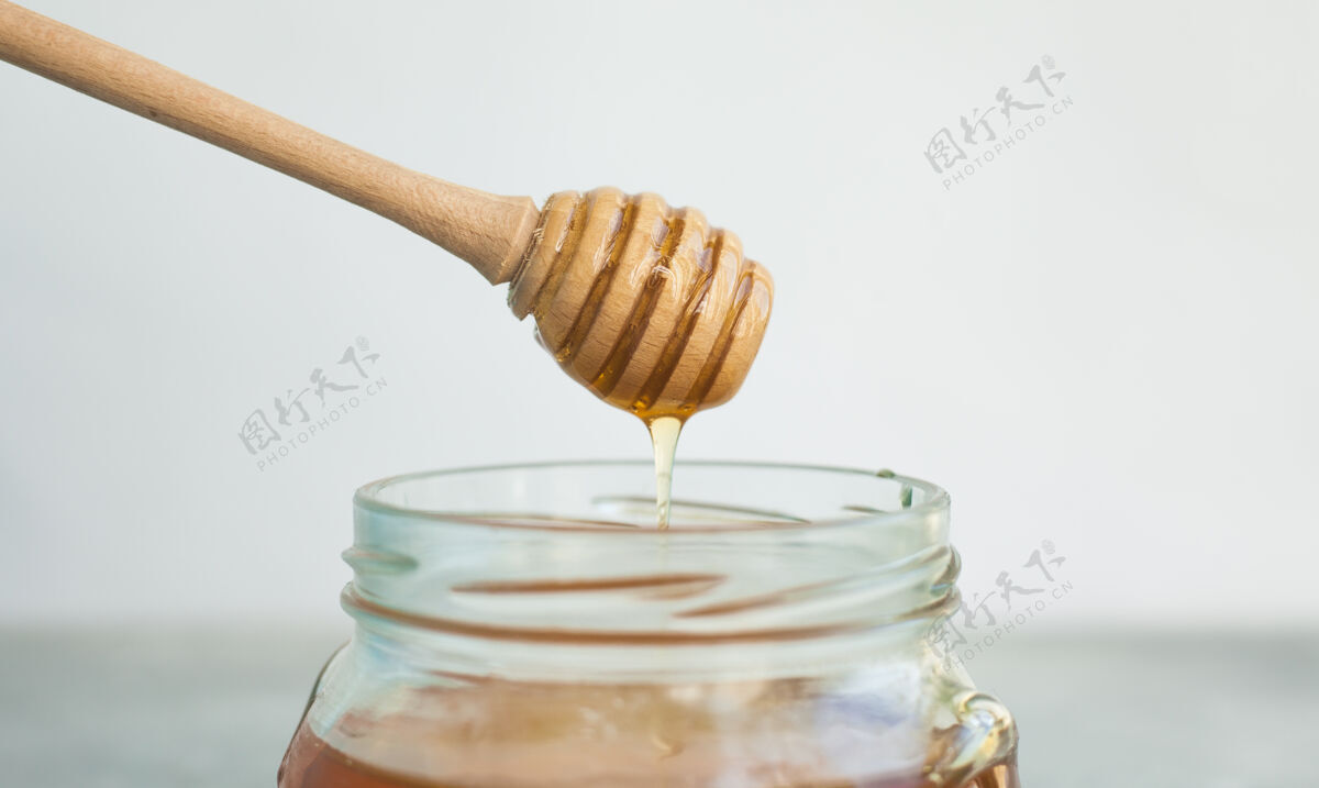 健康蜂蜜和蜂蜜勺放在灯上背景甜甜的在罐子里放蜂蜜 放文字滴滴流蜂窝