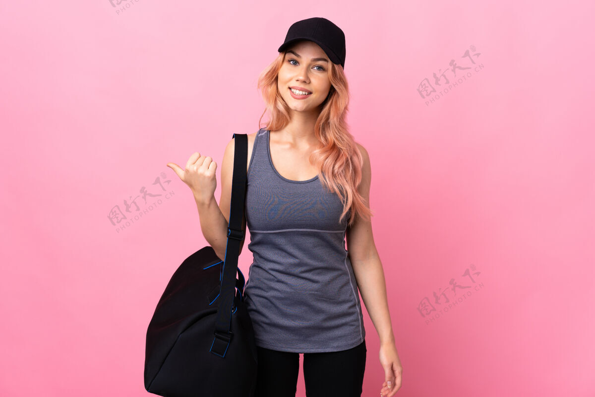 指十几岁的运动女子拿着运动包在孤立的背景上指着旁边展示一款产品右肖像护理
