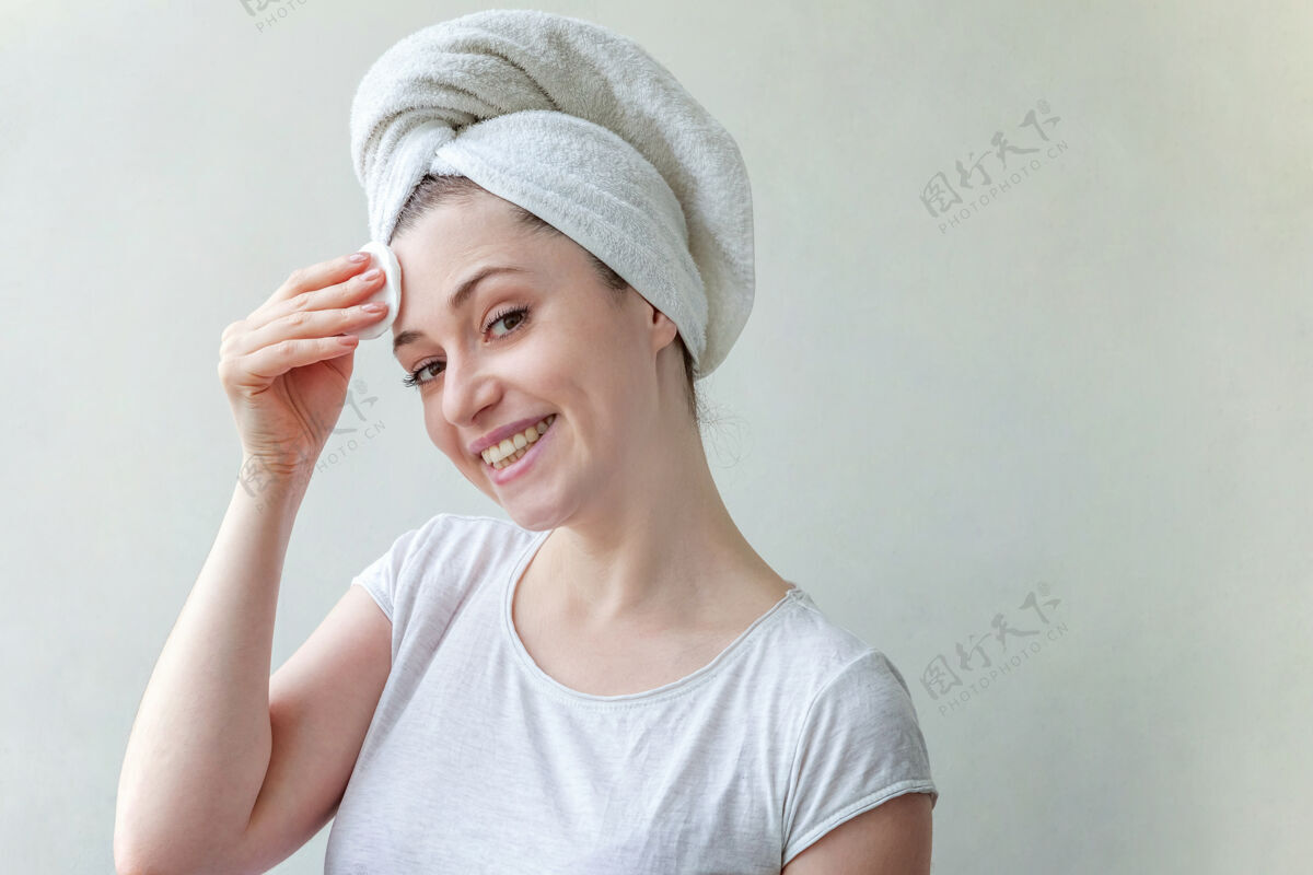 垫头上戴着毛巾的微笑女人的美丽肖像 柔软健康的皮肤 用隔离在白色背景上的化妆棉卸妆水疗毛孔皮肤护理