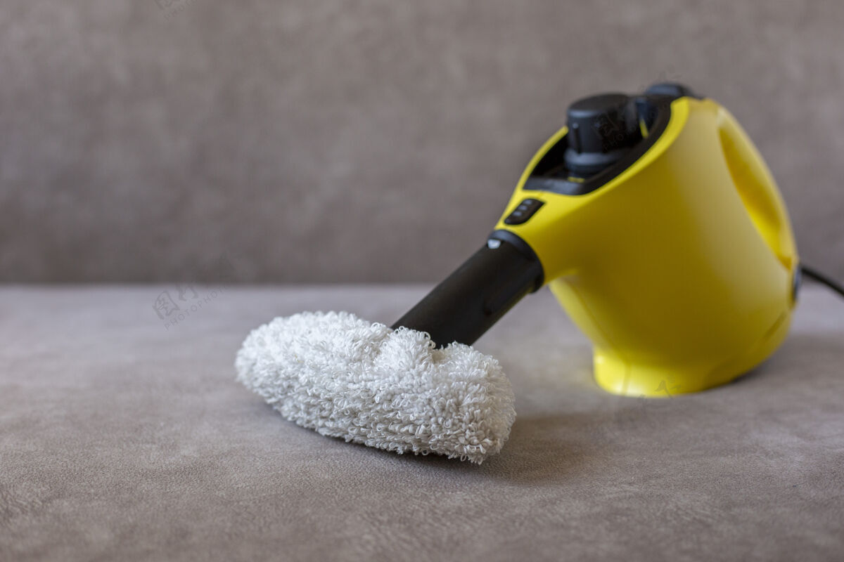 地毯黄色蒸汽清洁器和毛巾站在棕色沙发上 俯视图扫帚工具清扫