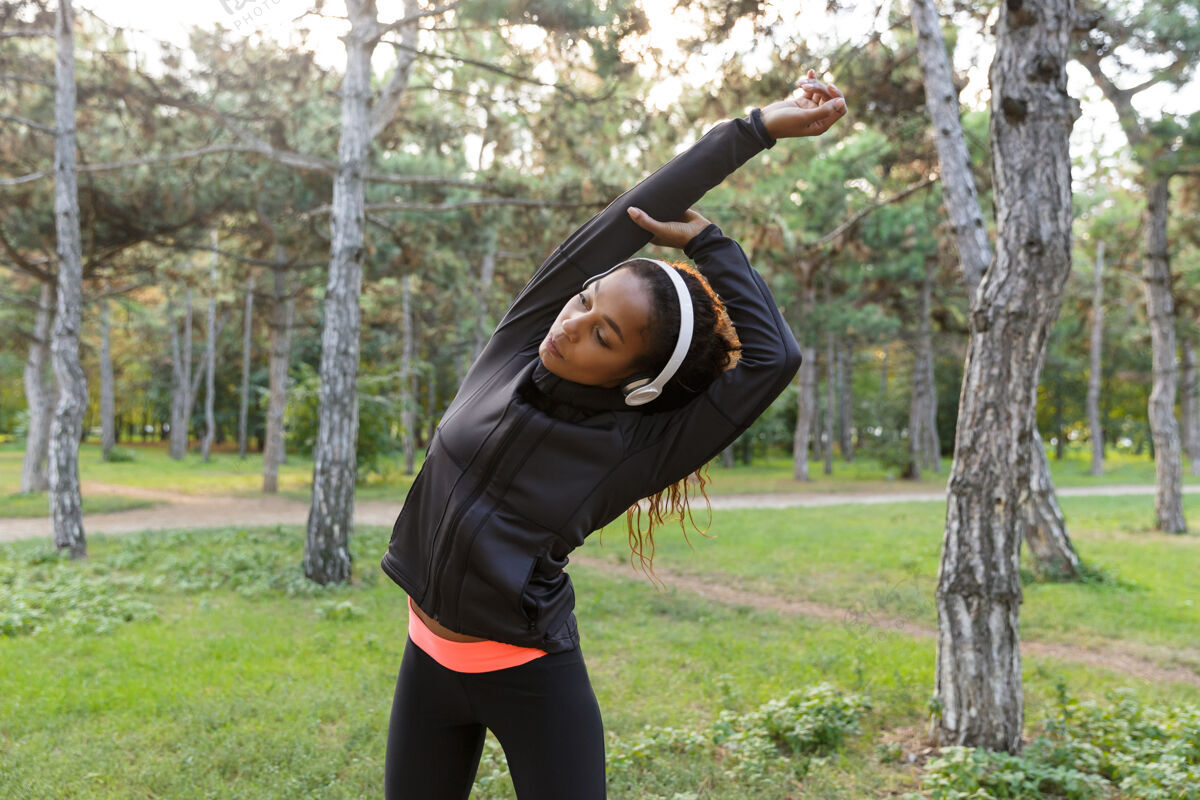 户外图为20多岁的健身女士穿着黑色运动服 在绿色公园锻炼身体精力充沛非洲女运动员