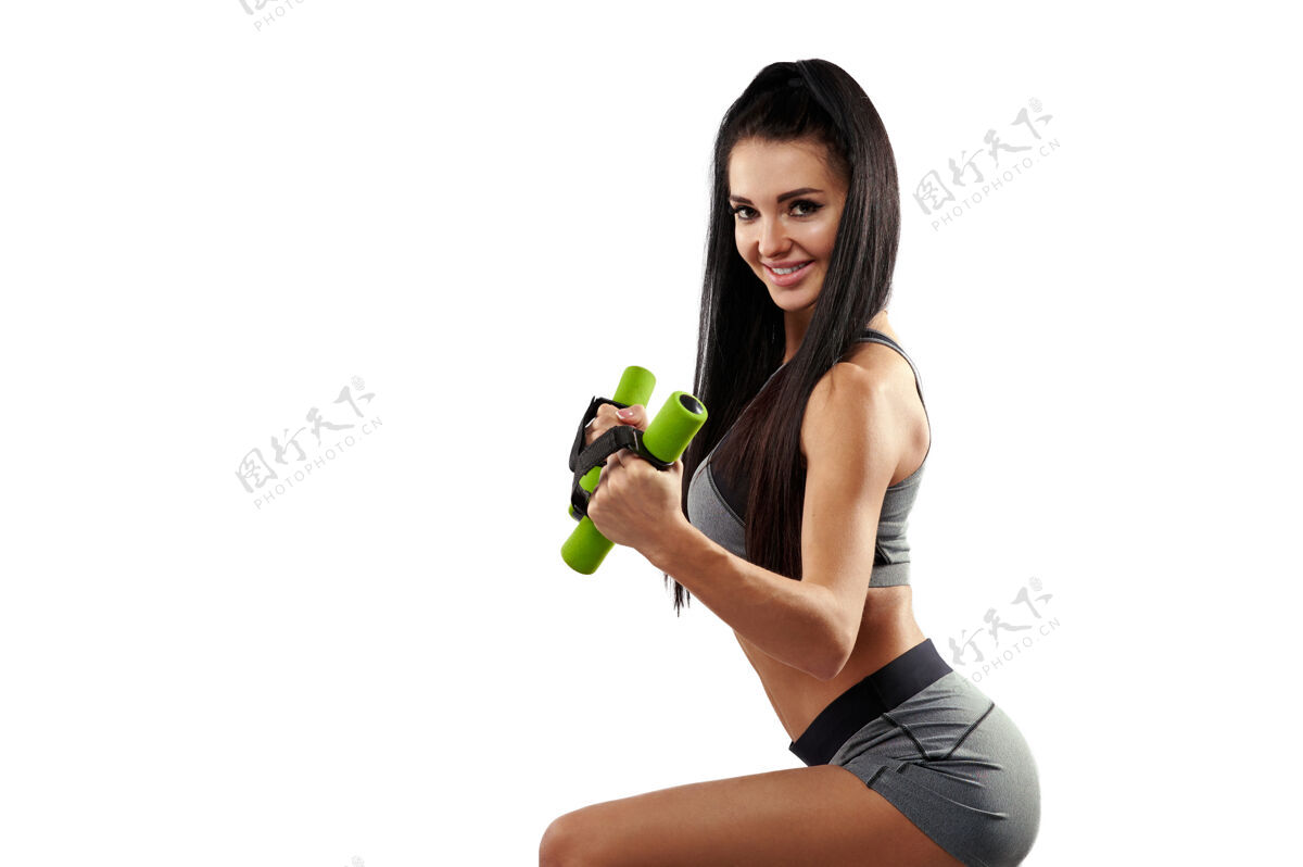 健身一个微笑健康的女人 留着长发 穿着运动服 手里拿着小哑铃腹肌运动装训练