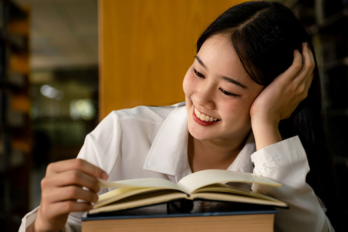 阅读年轻的亚洲女大学生在大学图书馆读书研究和向教科书学习学术站着大学