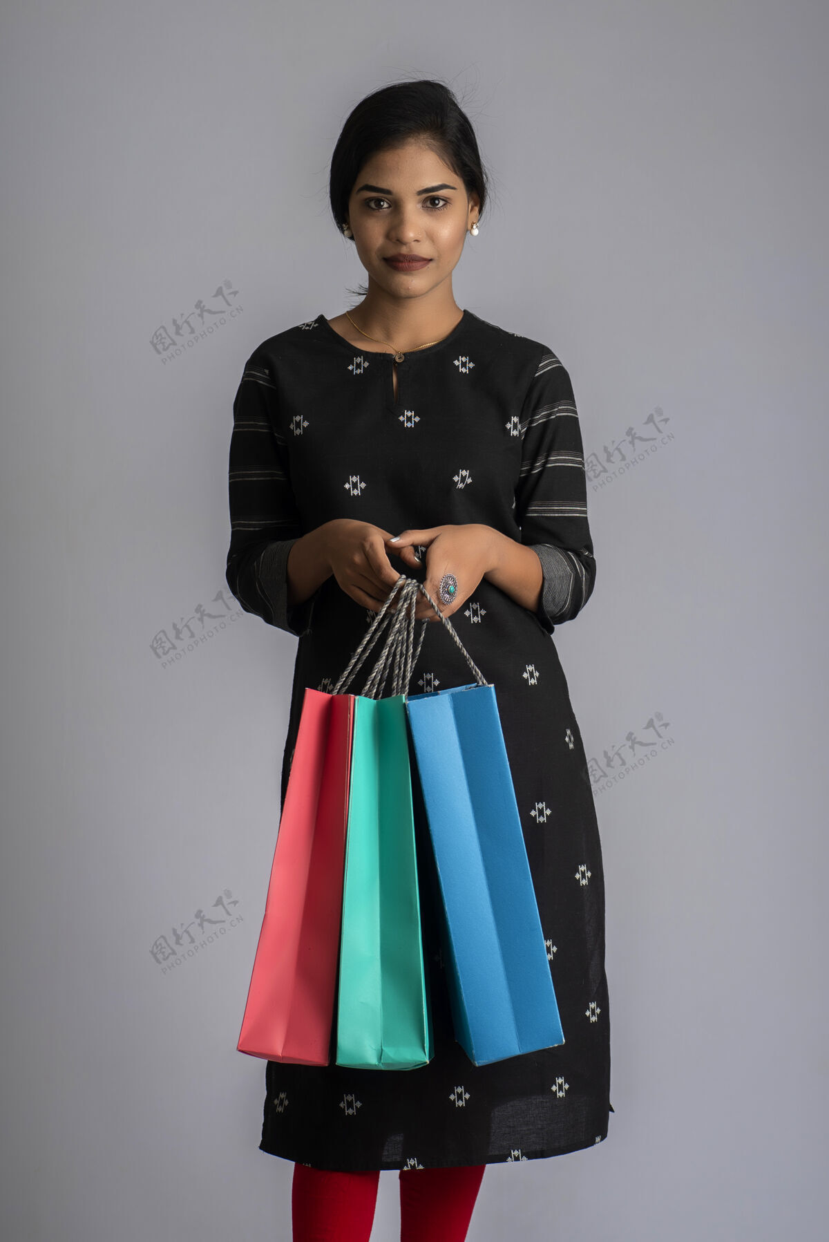 多彩美丽的印度女孩拿着购物袋摆姿势持有年轻购买