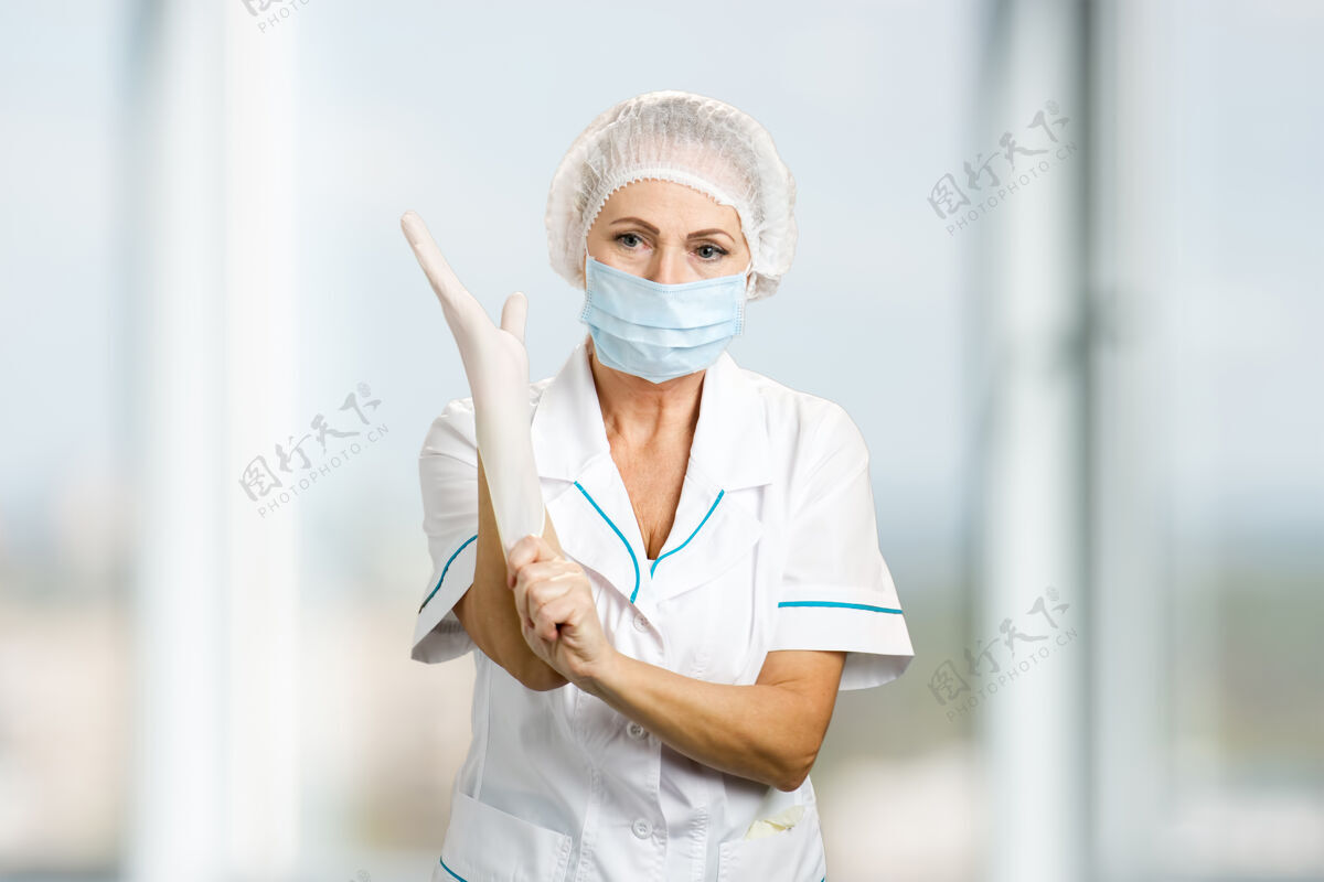信心女外科医生戴上手套女医生戴上防护口罩和帽子戴上白色防护手套 迷糊了制服帽子医生