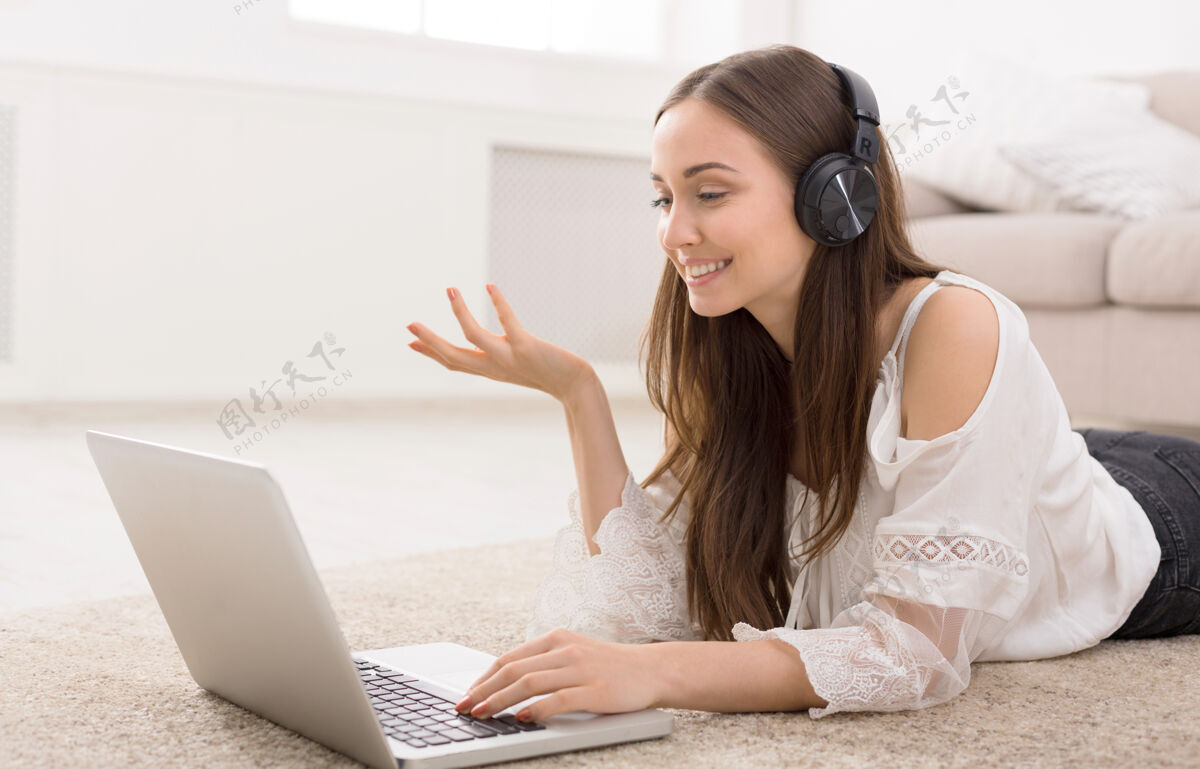 休闲戴着耳机的年轻女子在笔记本电脑上上网在线快乐笔记本电脑