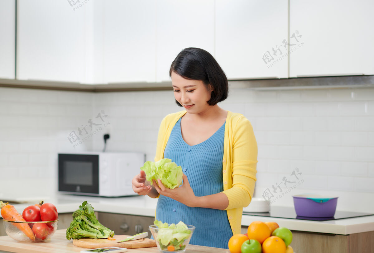 护理快乐的孕妇在家做饭 做新鲜的蔬菜沙拉 怀孕期间吃很多不同的蔬菜 健康的怀孕理念亚洲孕妇食物