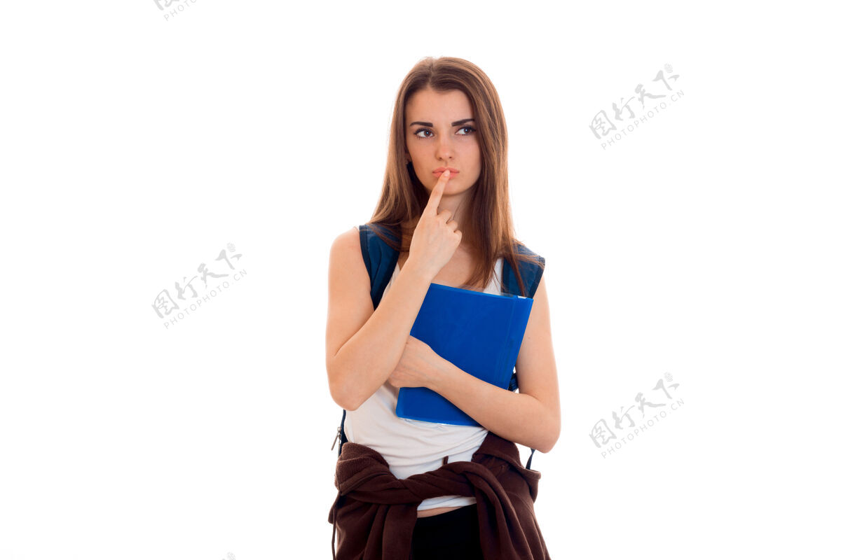 持有年轻严肃的女学生手里拿着蓝色的笔记本夹 在工作室的白墙上摆着孤立的姿势可爱现代锻炼