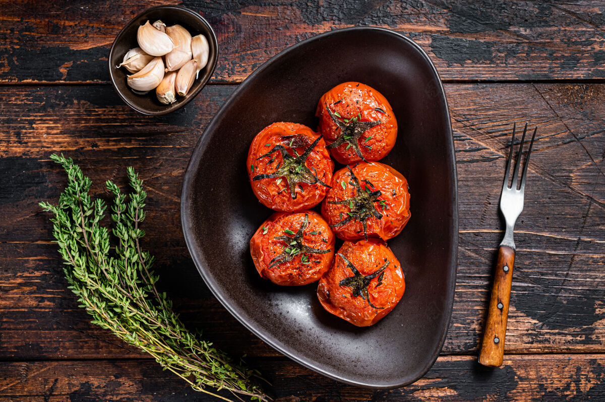 草药烤箱烤樱桃西红柿配百里香和大蒜在盘子里烧烤托盘健康