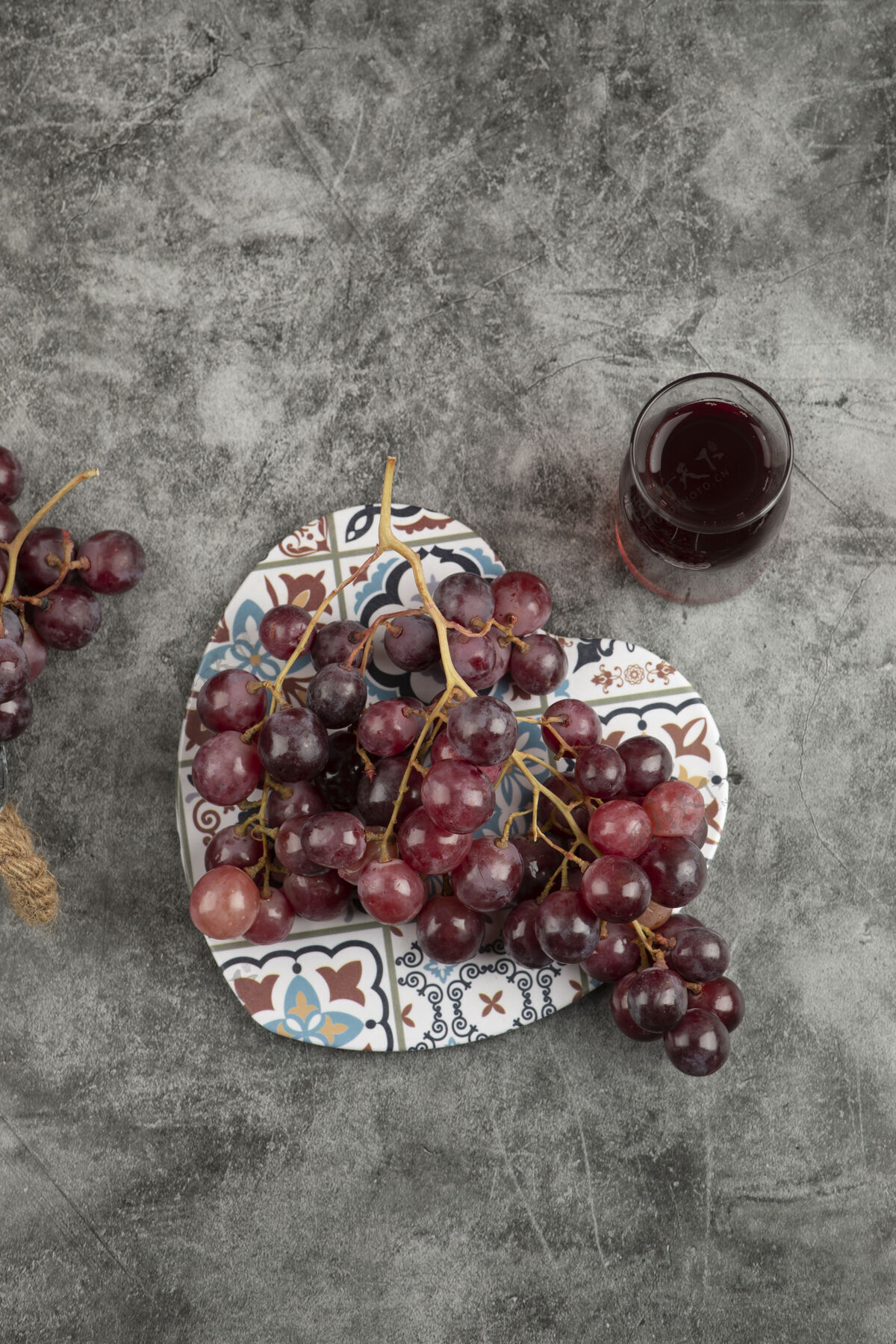 集群大理石桌上摆着一簇新鲜的红葡萄和一杯果汁成熟明亮酒庄