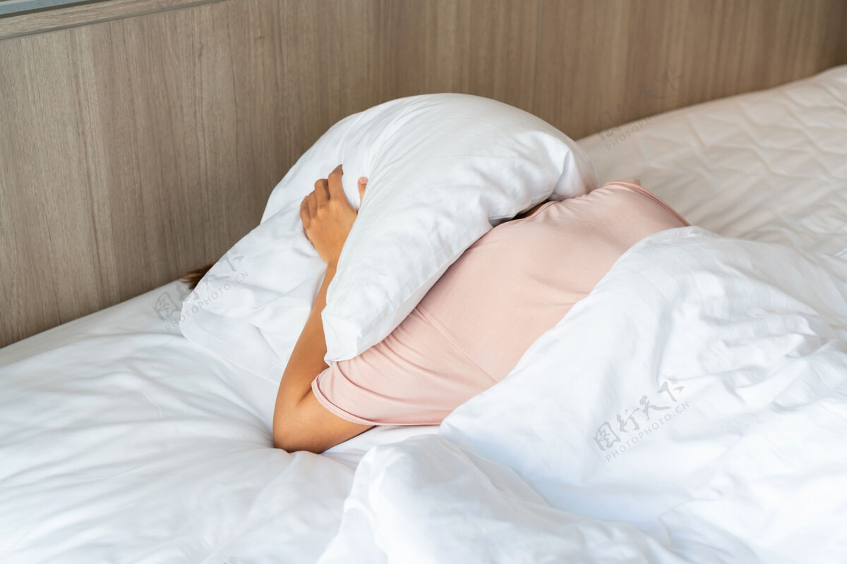 头躺在床上的人用枕头遮住头躲避阳光卧室醒来躺下
