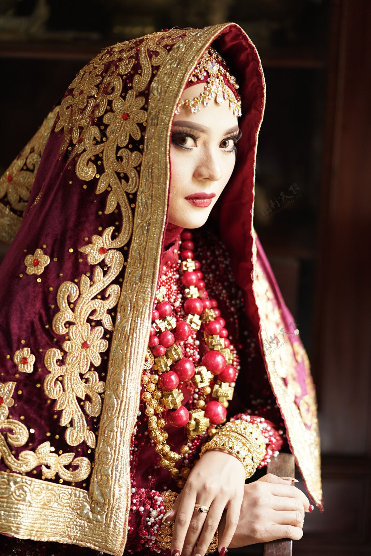 化妆一位身着金红色礼服的美丽印度新娘的肖像脸珠宝礼服