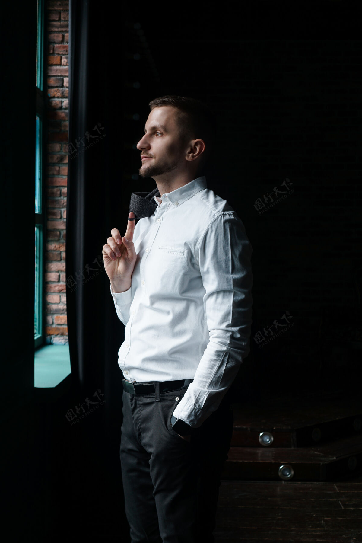 工作一个年轻的商人 穿着白衬衫站在窗边橱窗孤独成人