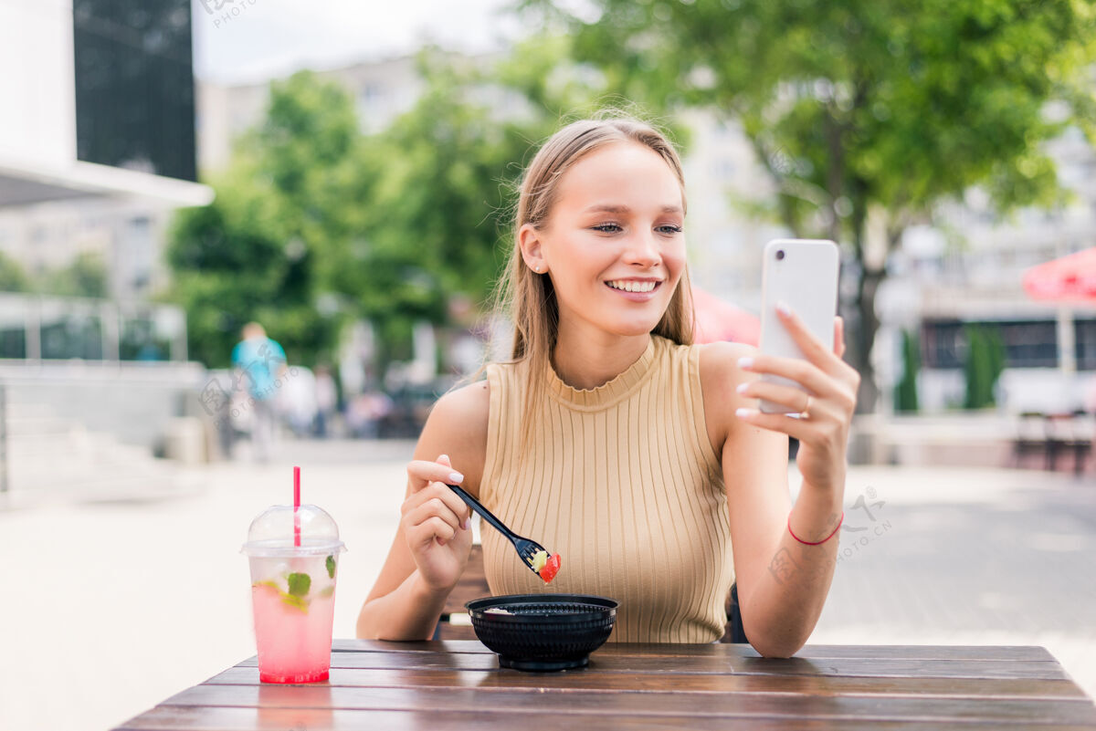 手机快乐女人拿着智能手机在街边咖啡馆自拍应用程序咖啡馆顾客