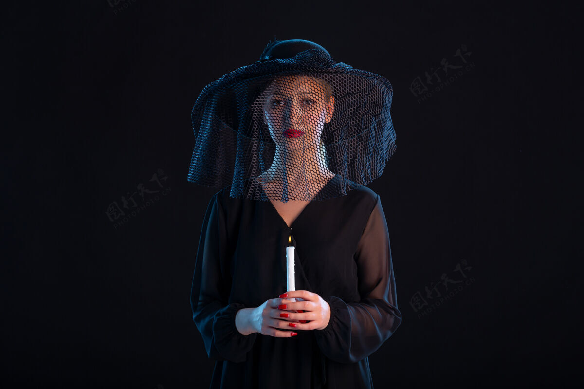 帽子悲伤的女人穿着黑色的衣服在黑色的桌子上点燃蜡烛死亡悲伤葬礼火悲伤男人