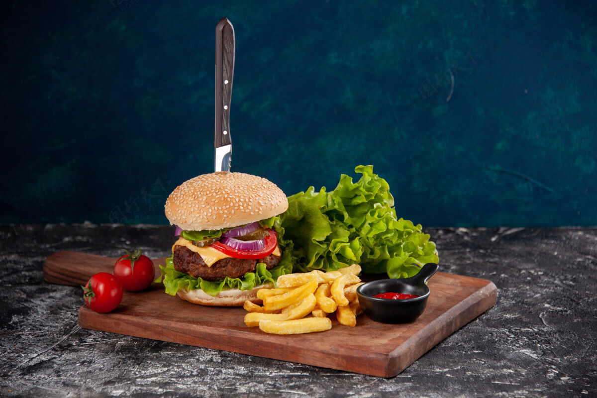 生菜刀在肉三明治和炸番茄干胡椒在木板番茄酱在深蓝色的表面饮食板番茄酱