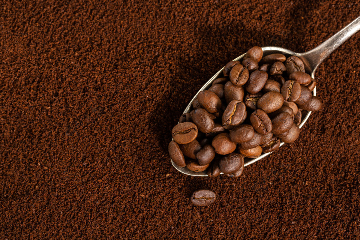 堆咖啡豆放在勺子上放在咖啡粉上特写美食自然有机